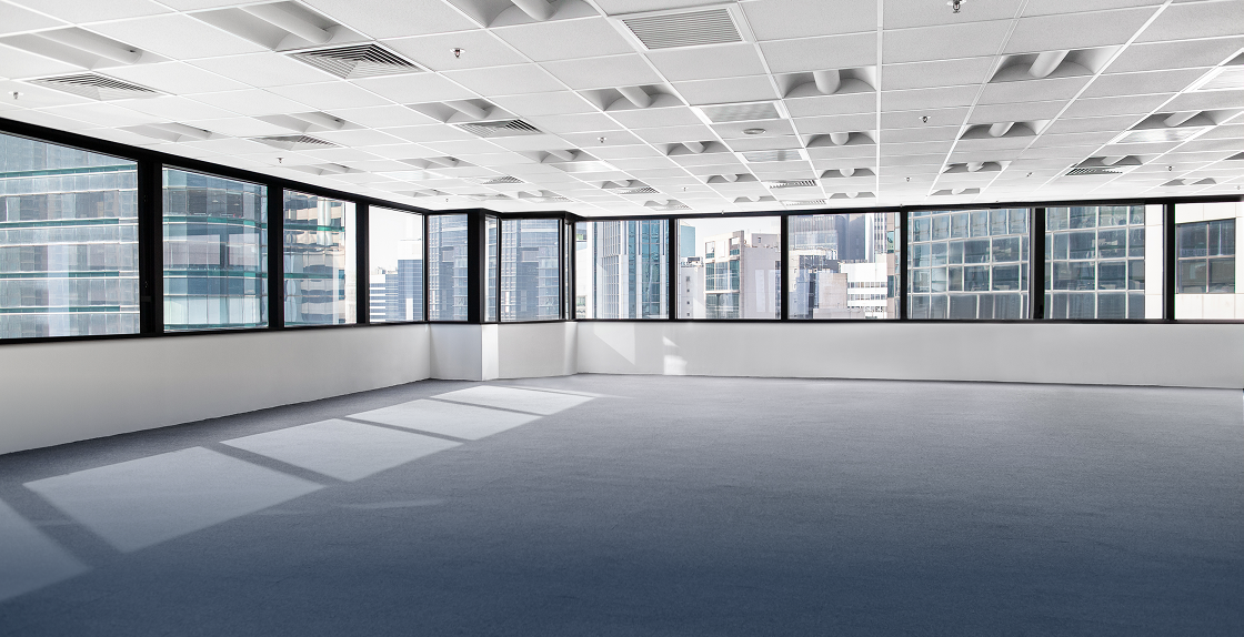 Empty office with large windows, a ceiling with lights, and a view of the buildings outside