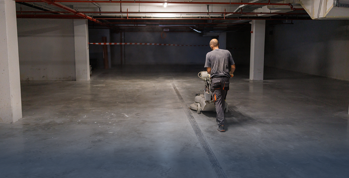 Man standing in a parking garage, holding a machine in his hand