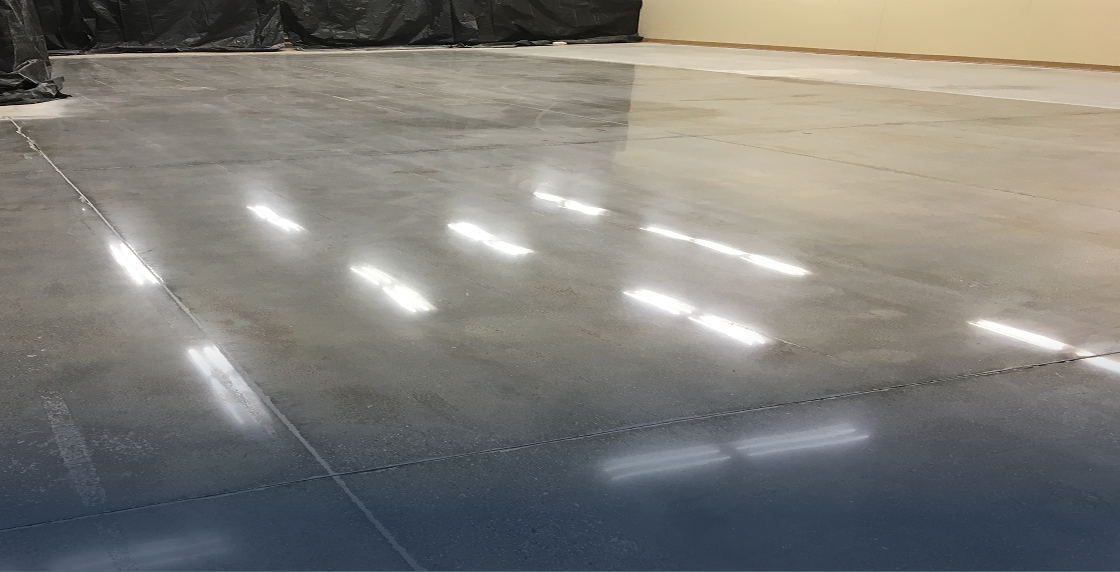 Concrete floor in a warehouse with a black tarp covering it, illuminated by lights on the floor